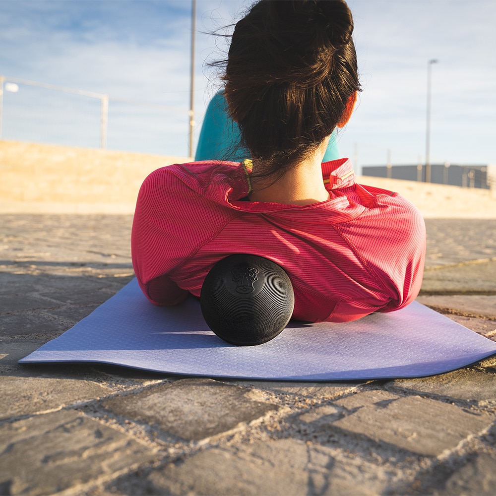Woman laying on Tiger Ball 5.0 to massage her back