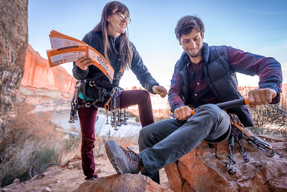 Couple laughing, the man is rolling his leg, while the woman holding Happy Muscles Book and showing where to roll