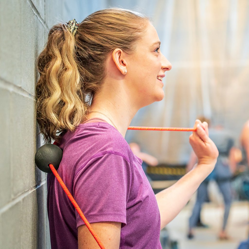 Woman Rolling her back with the Tiger Ball 2.6 Massage on a rope