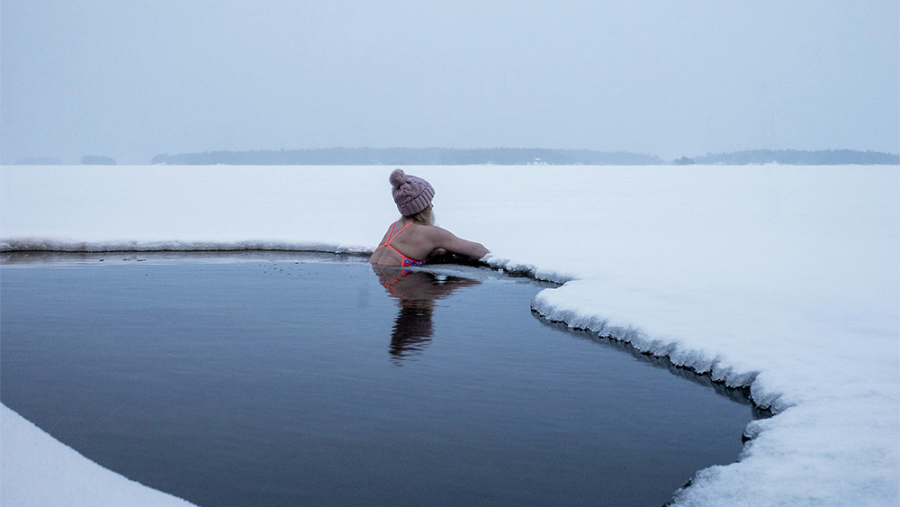 Woman relaxing in a cold lake surrounded by snow