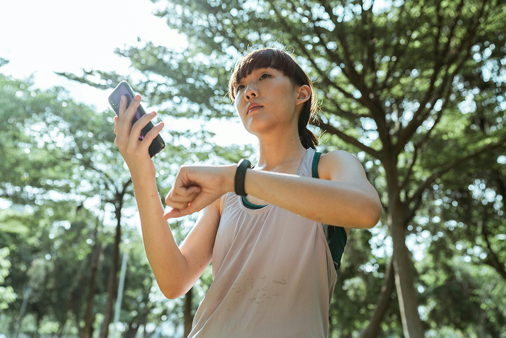 Young woman connecting smartphone and smart watch