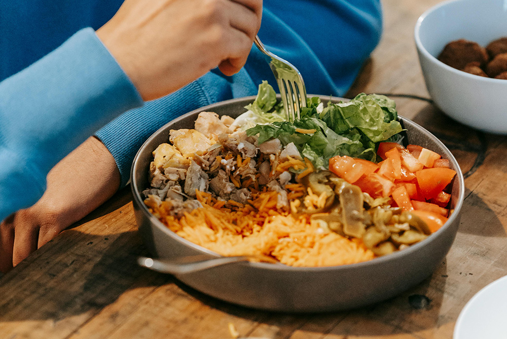 Man eating delicious dish with meat and vegetables