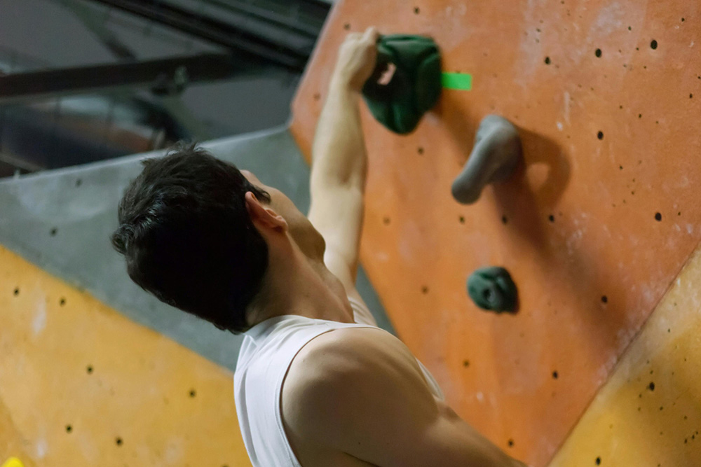 Man in White Tank Top Rock Climbing