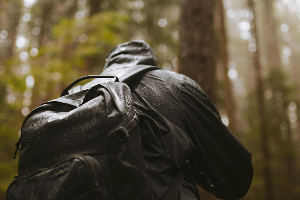 Back of a Male Hiker Wearing a Backpack in the rain