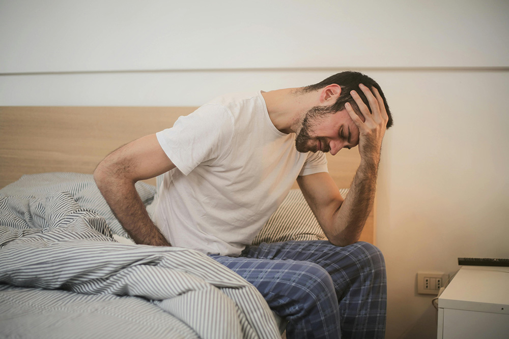 Man waking up from sleep with intense headache