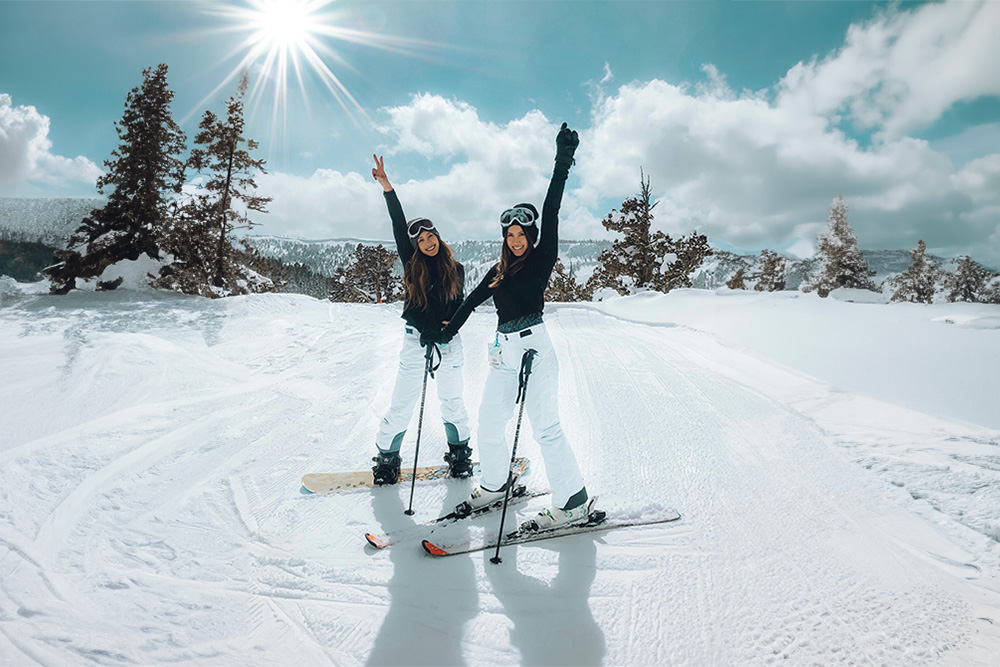 Two women posing before skiing on a sunny day