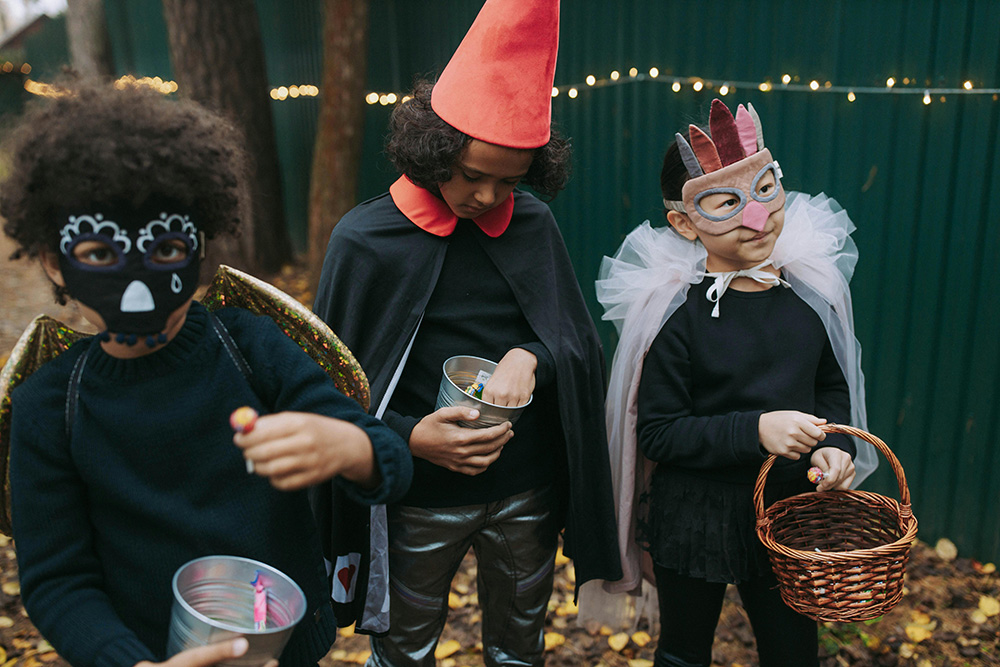 Three kids with Halloween costumes trick or treat