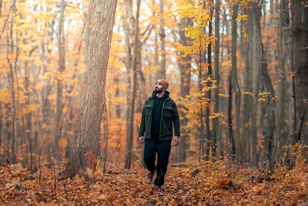 Man Walking in Autumn Forest Pathway