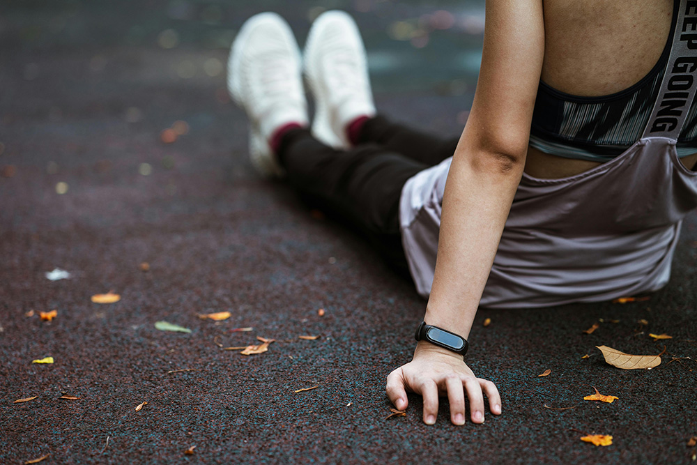 Woman sitting on sports ground with fitness watch