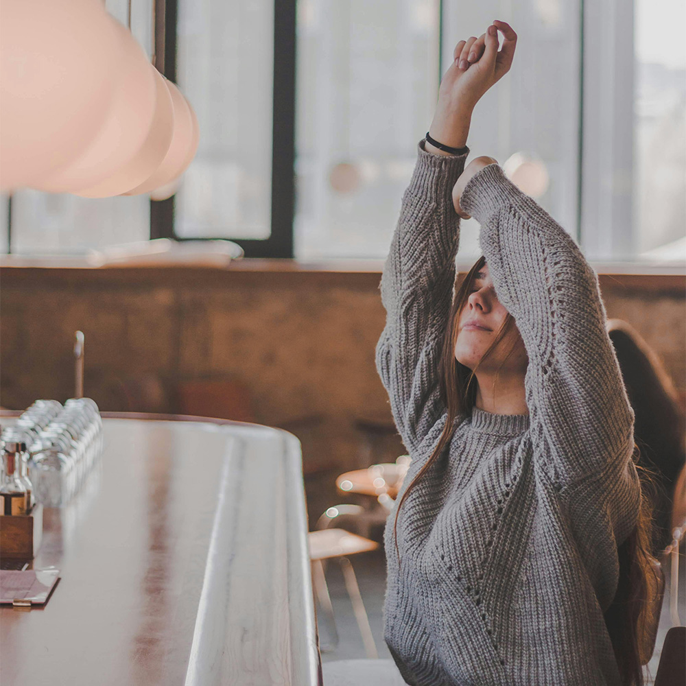 Woman In Grey Sweater Raising Both Of Her Arms stretching torso