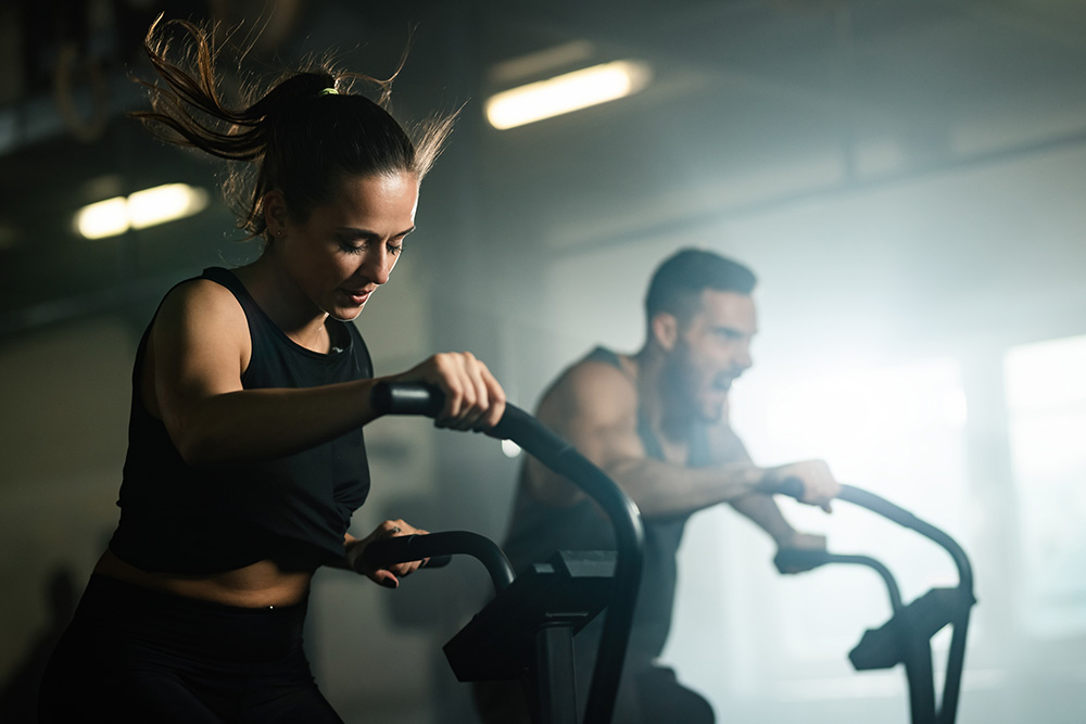 Young athletic woman having cross training on stationary bike in a gym